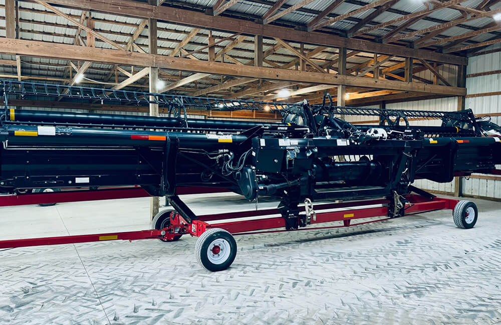 A black combine head inside a barn