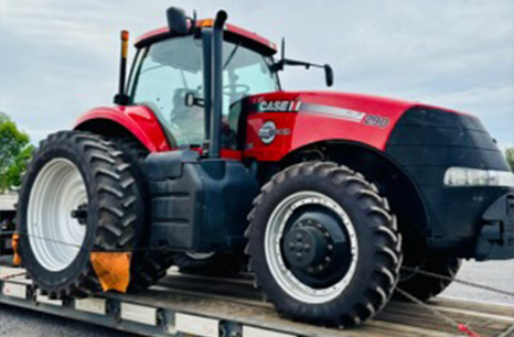 A Case 290 tractor being carried on a flat bed trailer