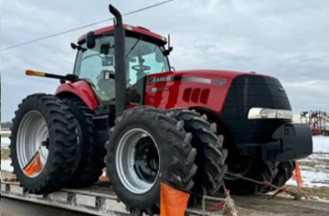 A case 305 being hauled on a flat bed trailer
