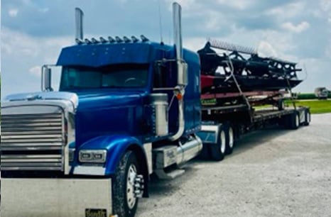 Blue semitruck hauling a combine head