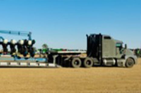 Gray sleeper truck hauling planter equipment