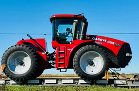 A Case IH 350 being hauled on a flatbed trailer