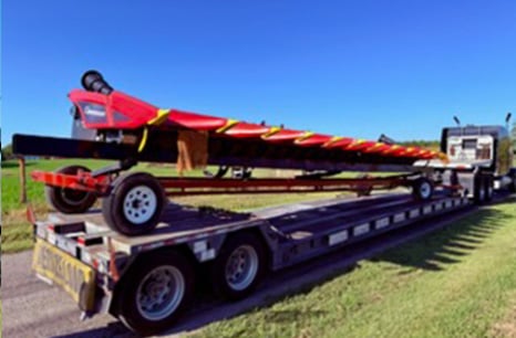 Red Planter Equipment being hauled by a semi truck