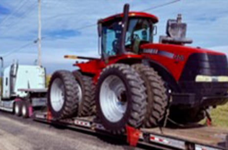 Large two wheeled Case IH tractor being hauled by a flat bed smei truck