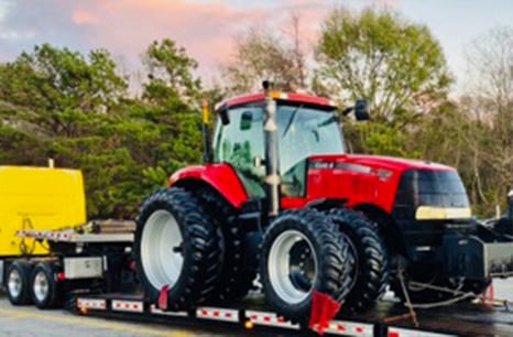 Case IH tractor being carried by a yellow semi truck  