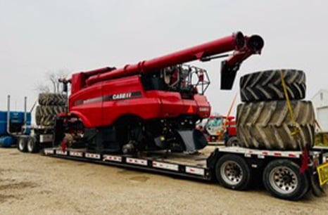 Semi truck carrying a Case IH combine truck and wheels on a flatbed truck
