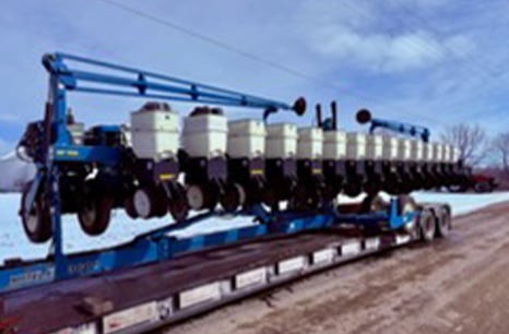 Blue planter equipment on a flatbed trailer
